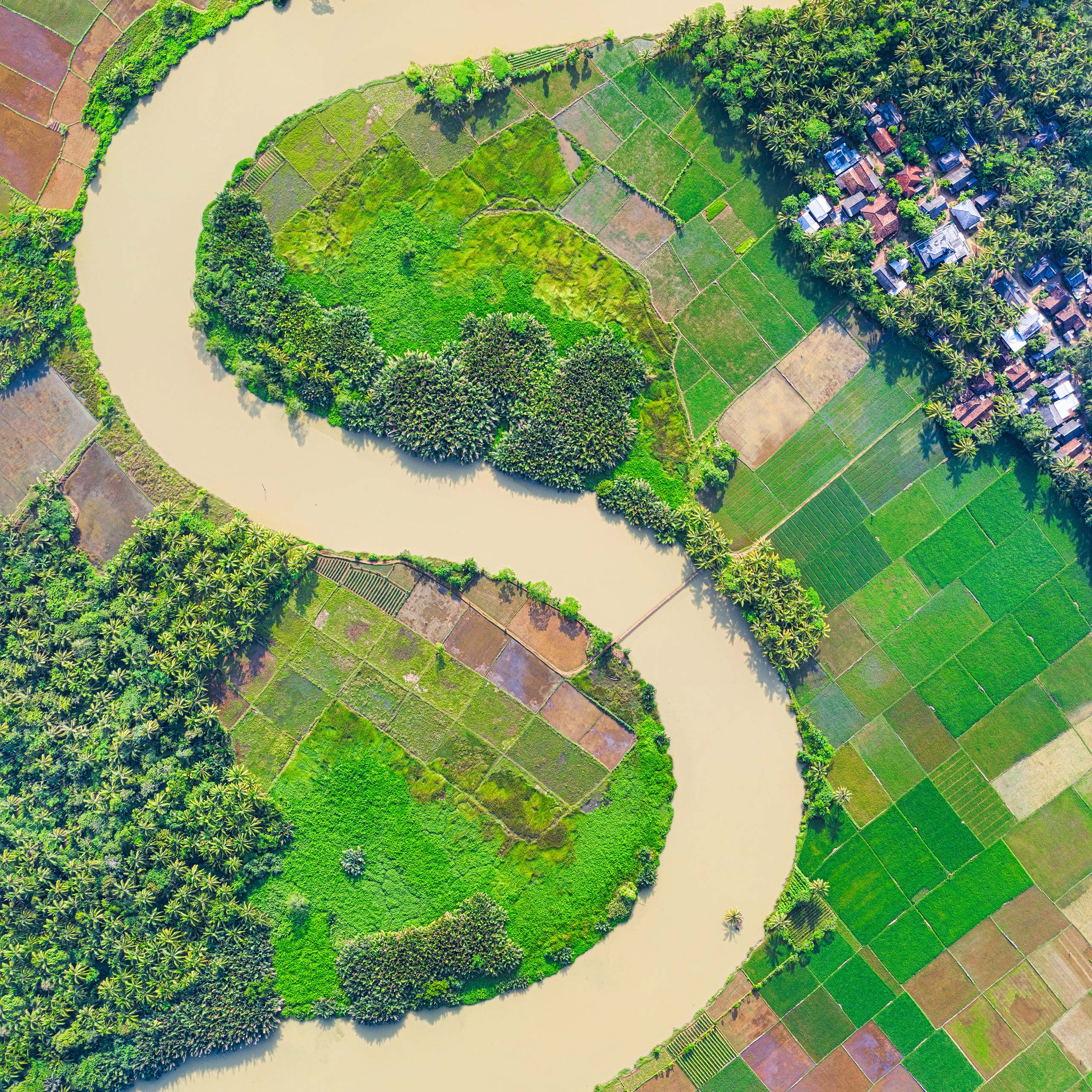 A birds-eye-view of an S-shaped river flowing through farm fields